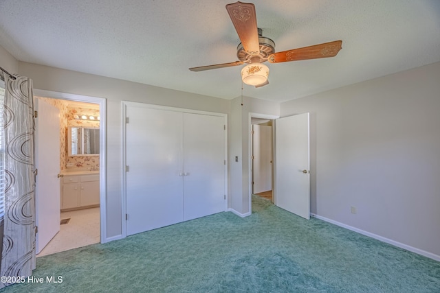 unfurnished bedroom featuring baseboards, a textured ceiling, a ceiling fan, carpet, and ensuite bath