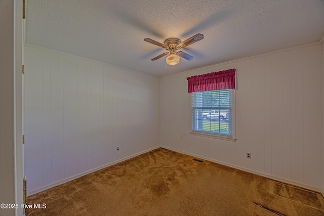 carpeted empty room with baseboards, ceiling fan, a textured ceiling, and visible vents
