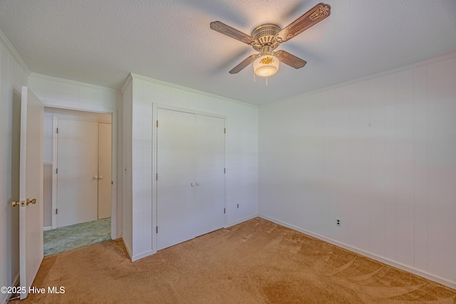 unfurnished bedroom with light colored carpet, ornamental molding, a textured ceiling, and a closet