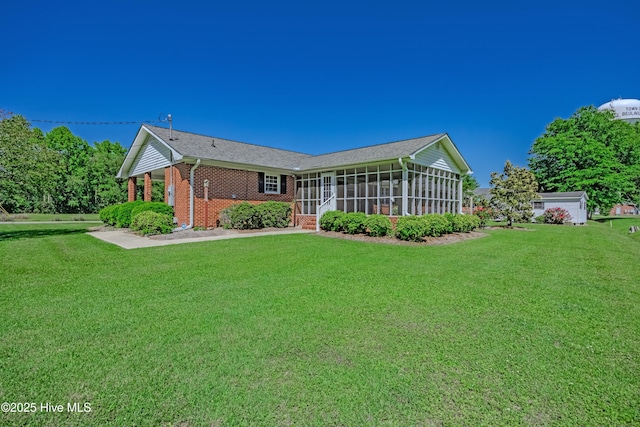 back of house featuring a yard, brick siding, and a sunroom