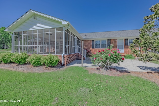 view of front of house with a sunroom, a front lawn, and brick siding