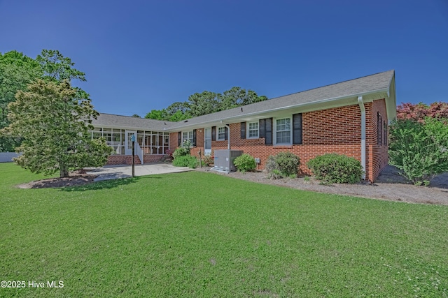 ranch-style house with a front yard, brick siding, central AC, a patio, and a shingled roof