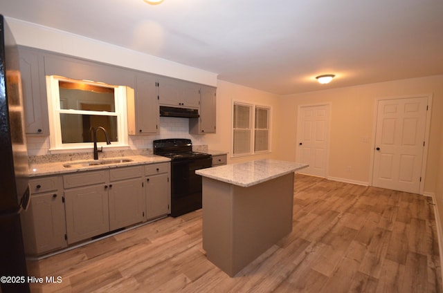 kitchen featuring black / electric stove, backsplash, a sink, freestanding refrigerator, and under cabinet range hood
