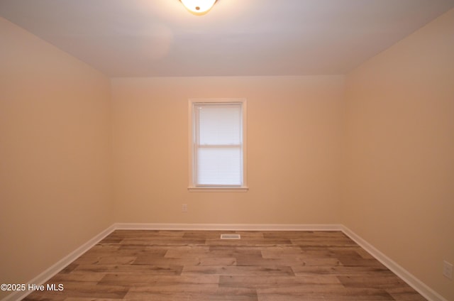 unfurnished room with baseboards, wood finished floors, and visible vents