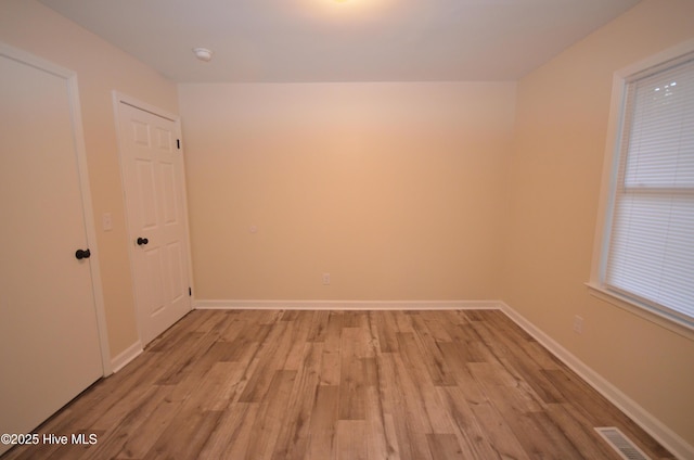 empty room with visible vents, light wood-style flooring, and baseboards