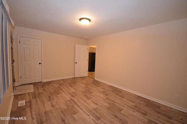 empty room with visible vents, baseboards, and wood finished floors