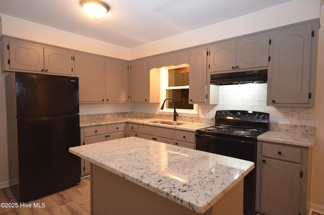 kitchen featuring gray cabinets, decorative backsplash, a sink, black appliances, and under cabinet range hood