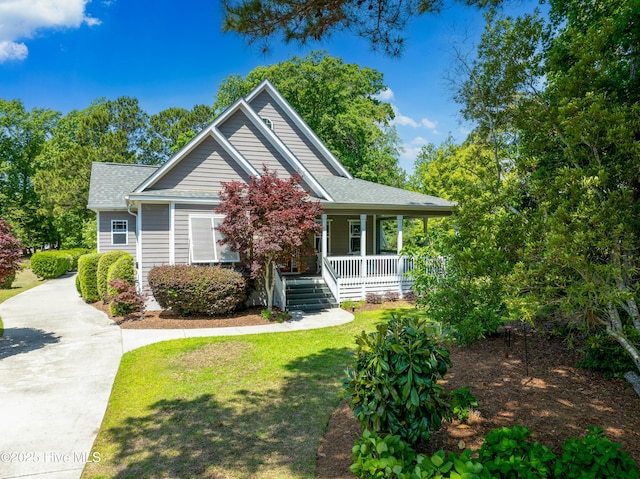 view of front of home with covered porch, a front yard, and roof with shingles