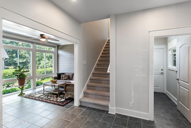 staircase featuring healthy amount of natural light, ceiling fan, tile patterned floors, and baseboards