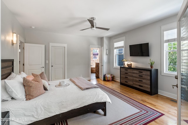 bedroom featuring light wood-style floors, baseboards, a ceiling fan, and ensuite bathroom