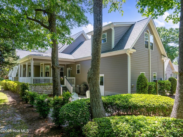rear view of property with a porch and roof with shingles