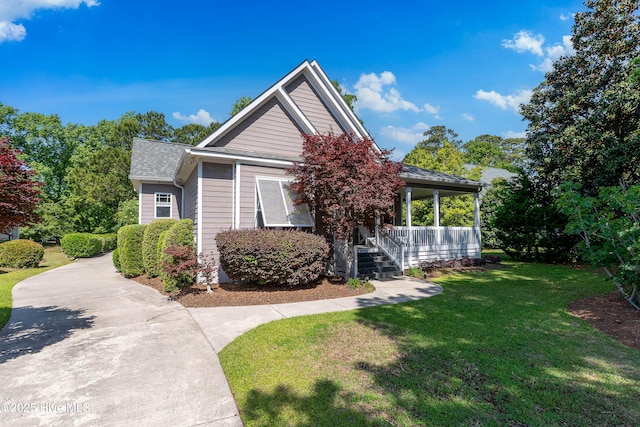 view of front of house with a porch, a front lawn, concrete driveway, and a shingled roof