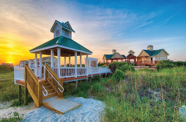 back of house at dusk with a gazebo and metal roof