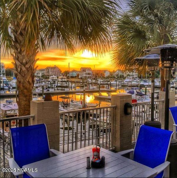 balcony at dusk featuring outdoor dining space and a water view