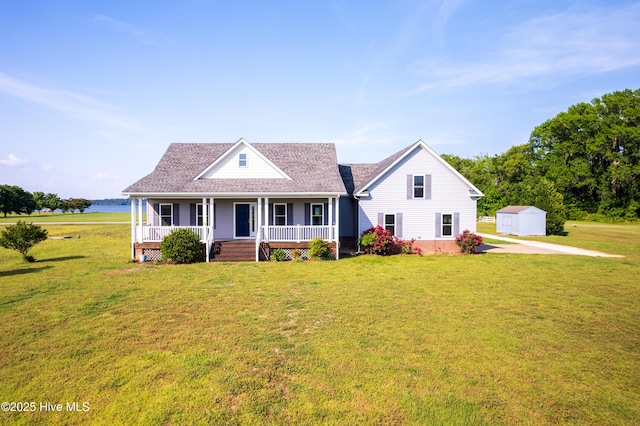 view of front of house with roof with shingles, a storage shed, a front yard, an outbuilding, and covered porch