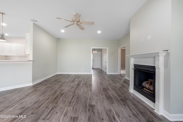 unfurnished living room with ceiling fan, a fireplace, recessed lighting, baseboards, and dark wood-style floors