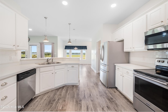 kitchen with a sink, appliances with stainless steel finishes, light wood-style floors, and white cabinetry