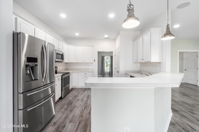 kitchen featuring a peninsula, wood finished floors, light countertops, tasteful backsplash, and stainless steel appliances