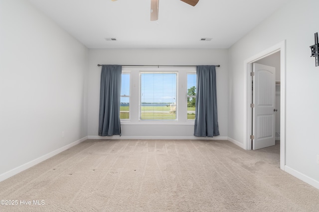 carpeted empty room with ceiling fan, visible vents, and baseboards