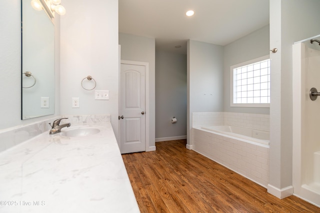 bathroom with vanity, baseboards, tiled tub, and wood finished floors