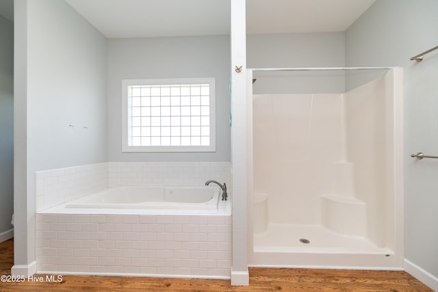 bathroom featuring a shower, baseboards, a garden tub, and wood finished floors