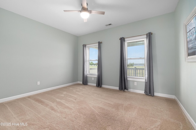 spare room featuring baseboards, ceiling fan, light carpet, and visible vents