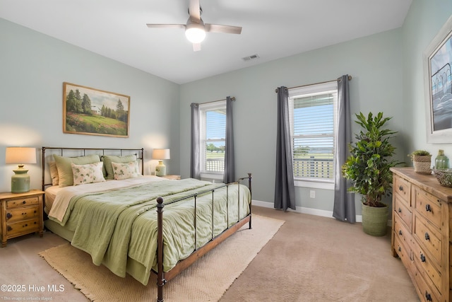 bedroom with baseboards, light carpet, a ceiling fan, and visible vents
