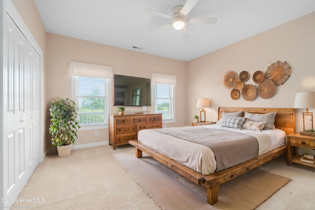bedroom featuring ceiling fan, light colored carpet, baseboards, visible vents, and a closet