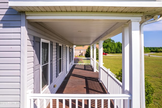 wooden terrace with a lawn and covered porch