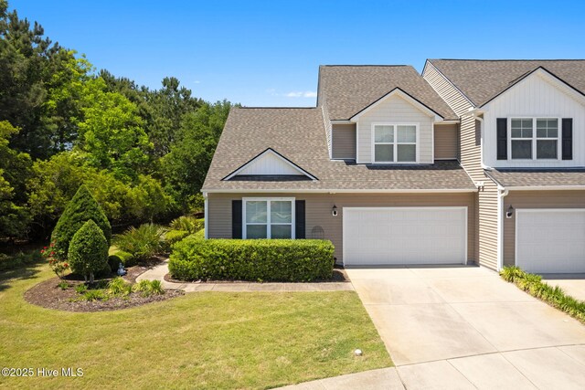 view of front of house with an attached garage, a front yard, a shingled roof, and driveway