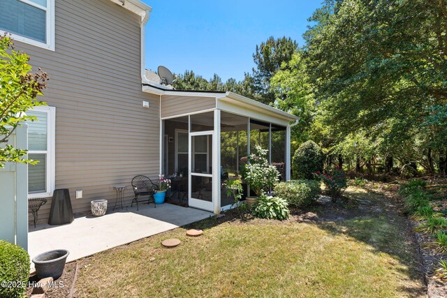 rear view of property featuring a sunroom, a lawn, and a patio