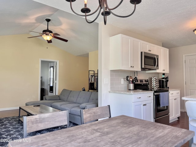 212 Red Carnation Dr, Holly Ridge, NC 28445 - kitchen with stainless steel appliances, dark wood-style flooring, white cabinets, open floor plan, and vaulted ceiling
