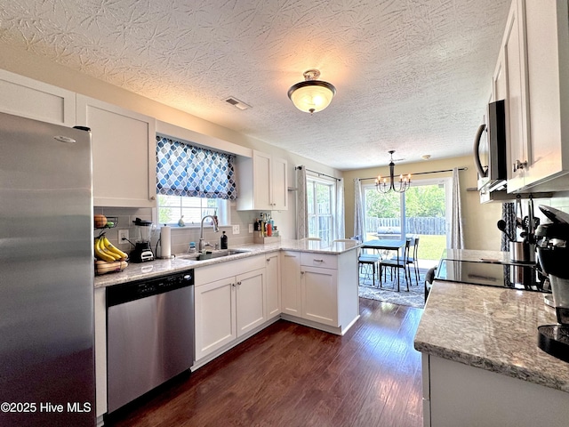 212 Red Carnation Dr, Holly Ridge, NC 28445 - kitchen featuring a sink, appliances with stainless steel finishes, a peninsula, white cabinets, and dark wood-style floors