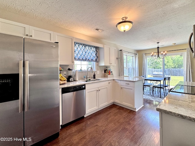 212 Red Carnation Dr, Holly Ridge, NC 28445 - kitchen with stainless steel appliances, a sink, dark wood-style flooring, a peninsula, and white cabinetry