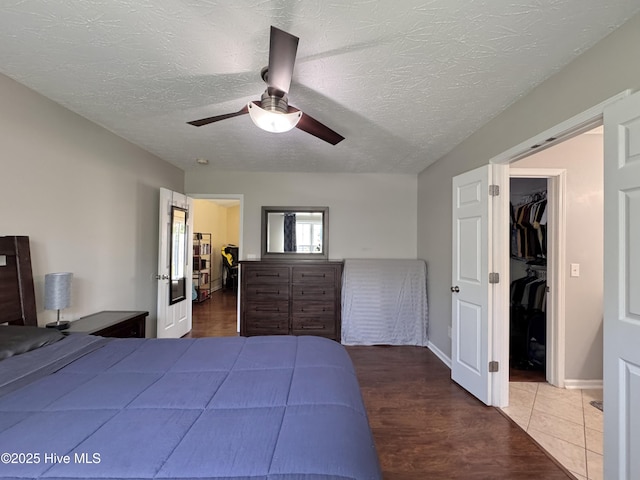 212 Red Carnation Dr, Holly Ridge, NC 28445 - bedroom featuring a walk in closet, a ceiling fan, a closet, a textured ceiling, and baseboards
