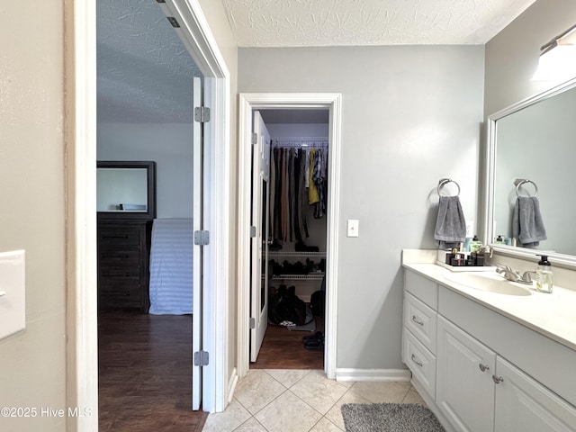 212 Red Carnation Dr, Holly Ridge, NC 28445 - bathroom featuring vanity, tile patterned flooring, a textured ceiling, and a walk in closet