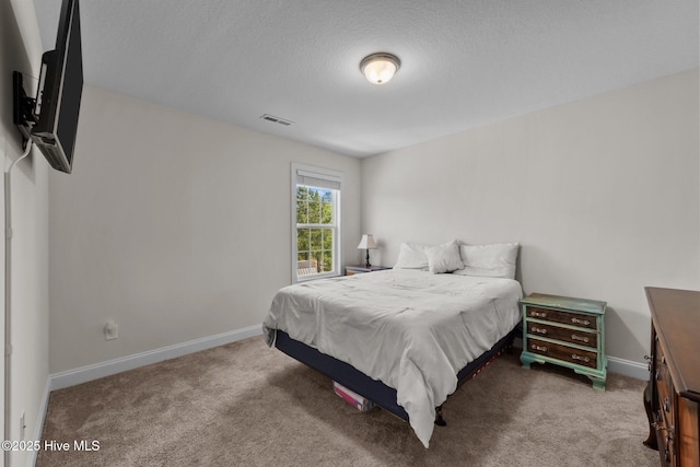 bedroom featuring baseboards, carpet flooring, visible vents, and a textured ceiling