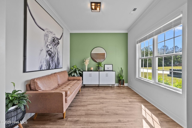 living area with ornamental molding, baseboards, visible vents, and wood finished floors