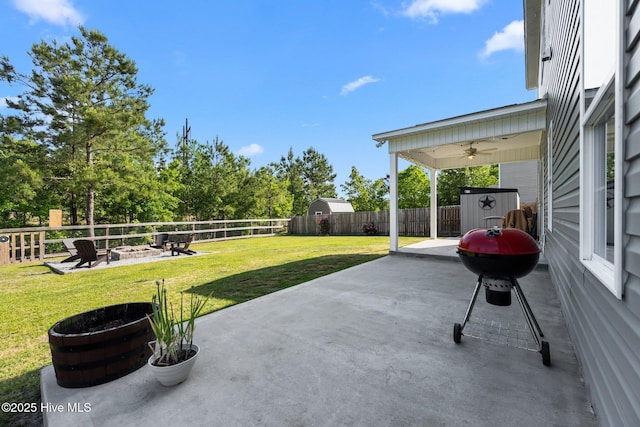 view of patio featuring a ceiling fan, a shed, an outdoor structure, an outdoor fire pit, and a fenced backyard
