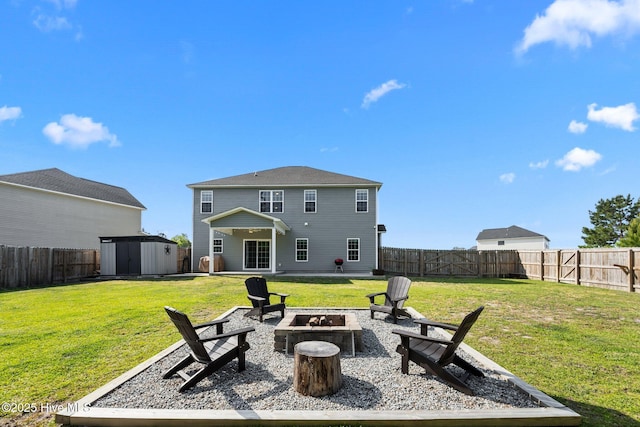 rear view of house featuring a fenced backyard, a fire pit, a shed, and a lawn