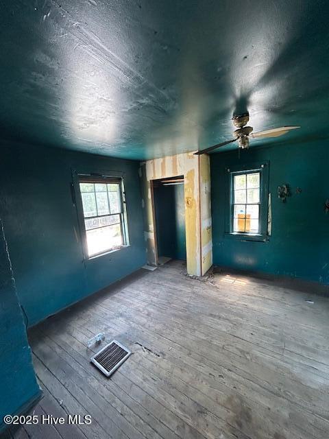 spare room with a textured ceiling, ceiling fan, visible vents, and hardwood / wood-style floors