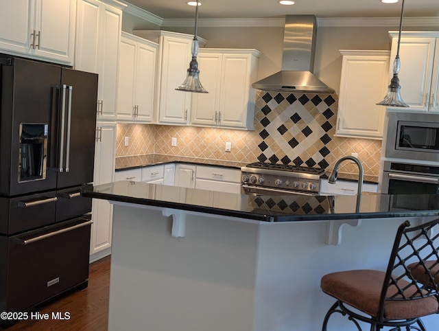 kitchen featuring wall chimney range hood, high quality appliances, dark countertops, and a kitchen bar