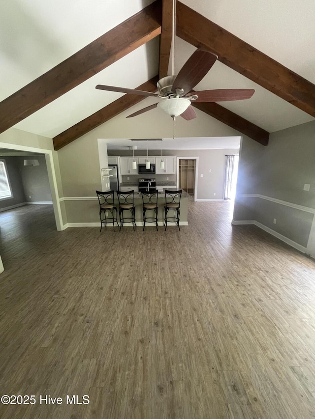 dining area with baseboards, lofted ceiling with beams, and wood finished floors