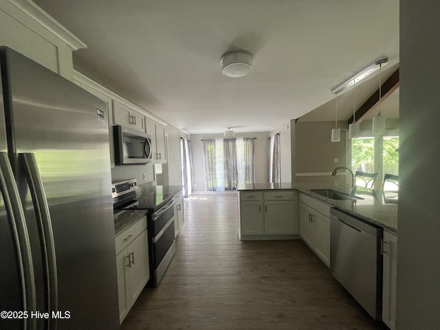 kitchen with a sink, appliances with stainless steel finishes, white cabinets, and dark wood-style floors