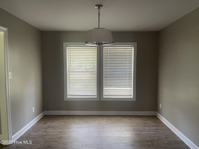 unfurnished dining area featuring a healthy amount of sunlight, baseboards, and wood finished floors