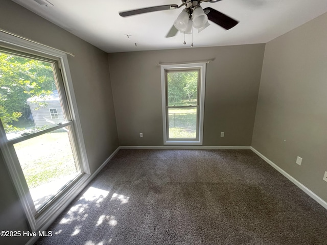 carpeted empty room featuring baseboards, ceiling fan, and a wealth of natural light