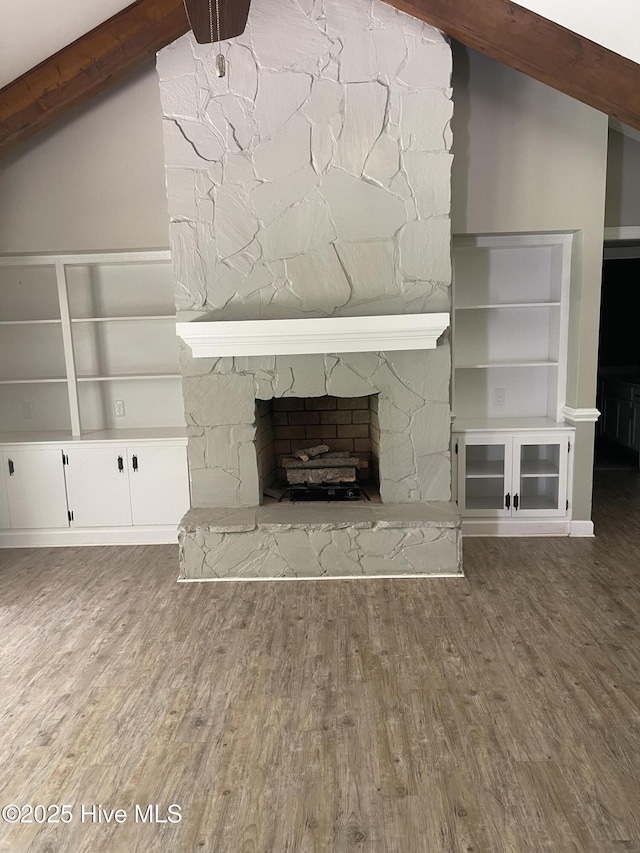 unfurnished living room with vaulted ceiling with beams, wood finished floors, and a fireplace