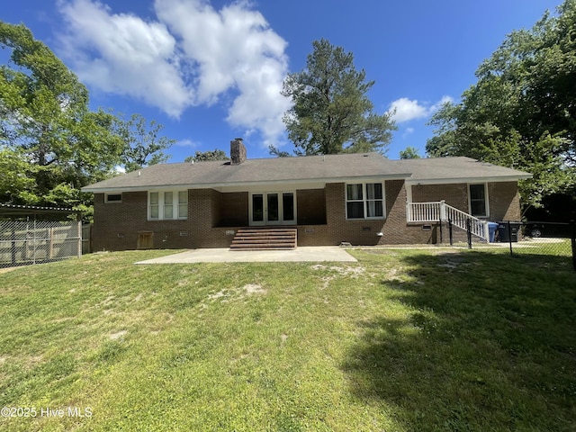back of house featuring fence, a patio, a chimney, brick siding, and a yard