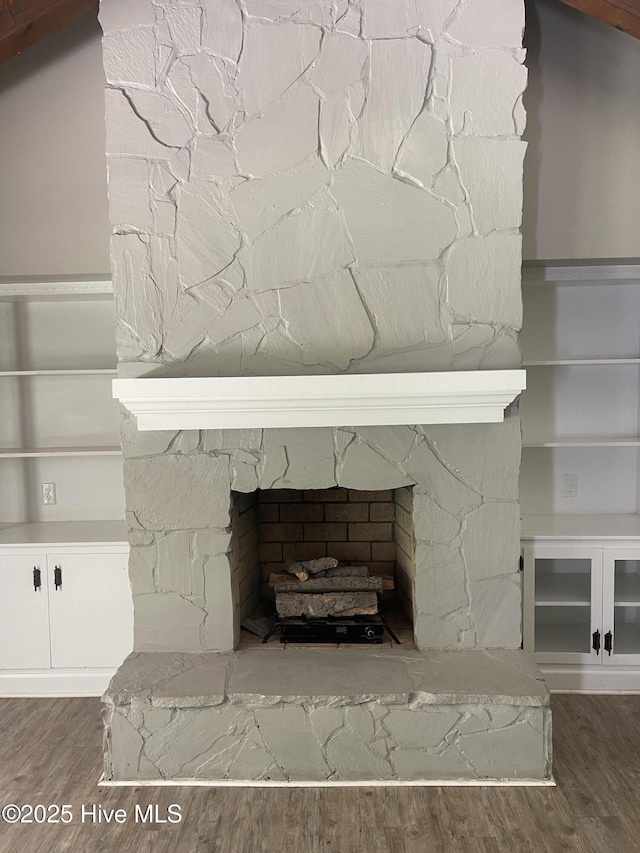 details with a stone fireplace and wood finished floors