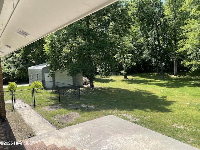 view of yard with a gate, a detached garage, fence, an outdoor structure, and a patio